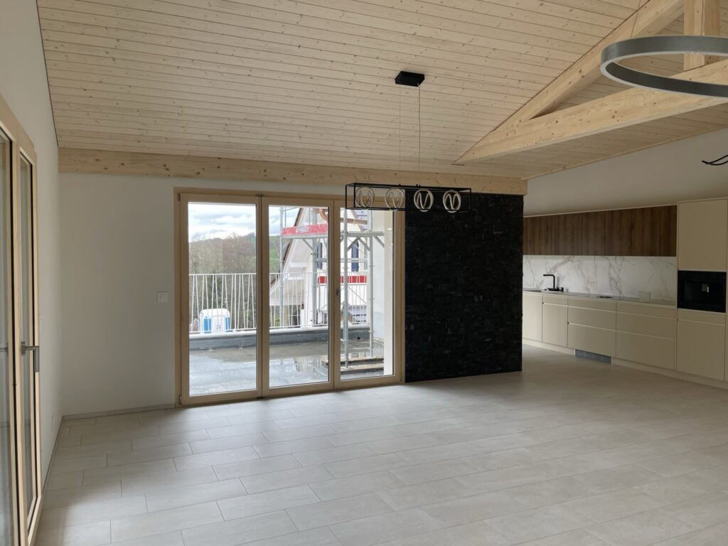 Séjour sous charpente avec baie vitrée, rénové par Home Création Architecture, entreprise de rénovation à Vevey